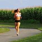 a female athlete running in the park with pink weights